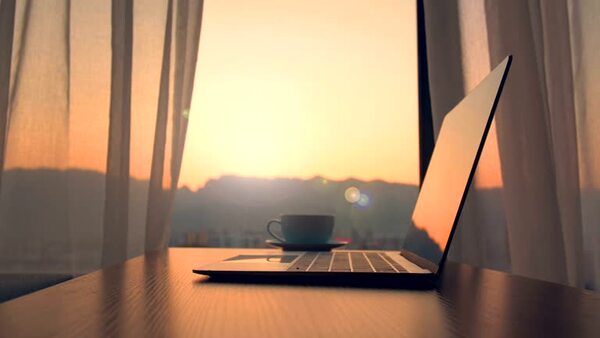 A laptop on a desk near a window with daylight